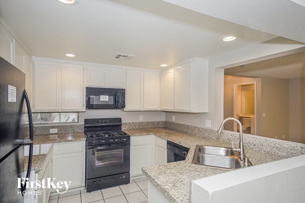 A kitchen with granite countertops and white cabinets.