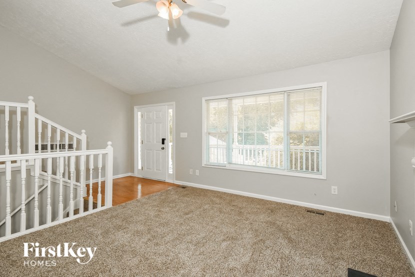 an empty living room with a ceiling fan and a window