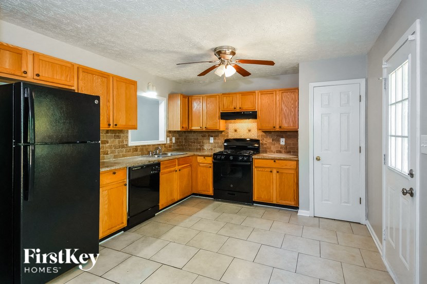 a kitchen with wooden cabinets and black appliances and a ceiling fan