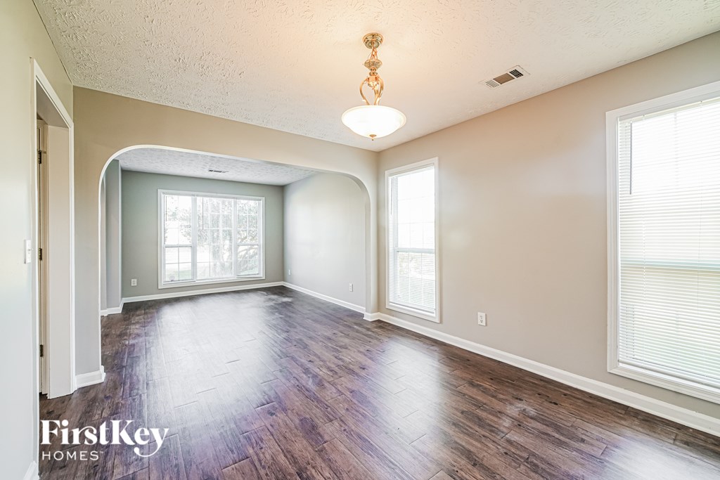 A spacious room with wooden floors and a large window.