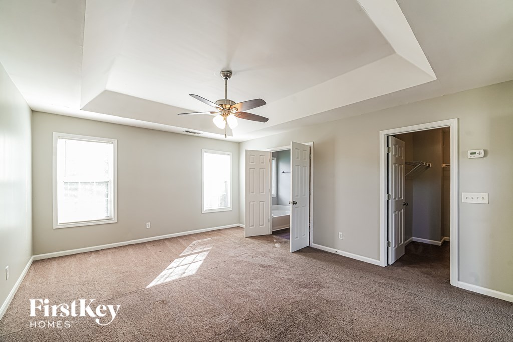 A spacious room with a ceiling fan and a carpeted floor.
