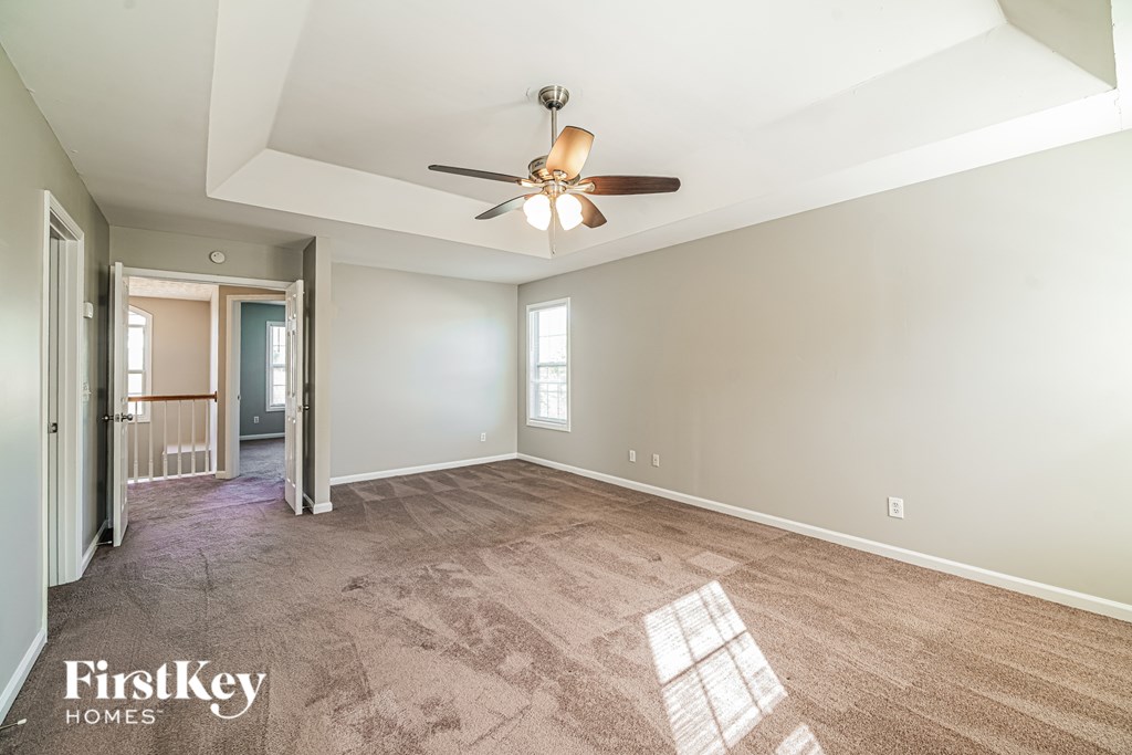 A spacious room with a ceiling fan and carpeted floor.