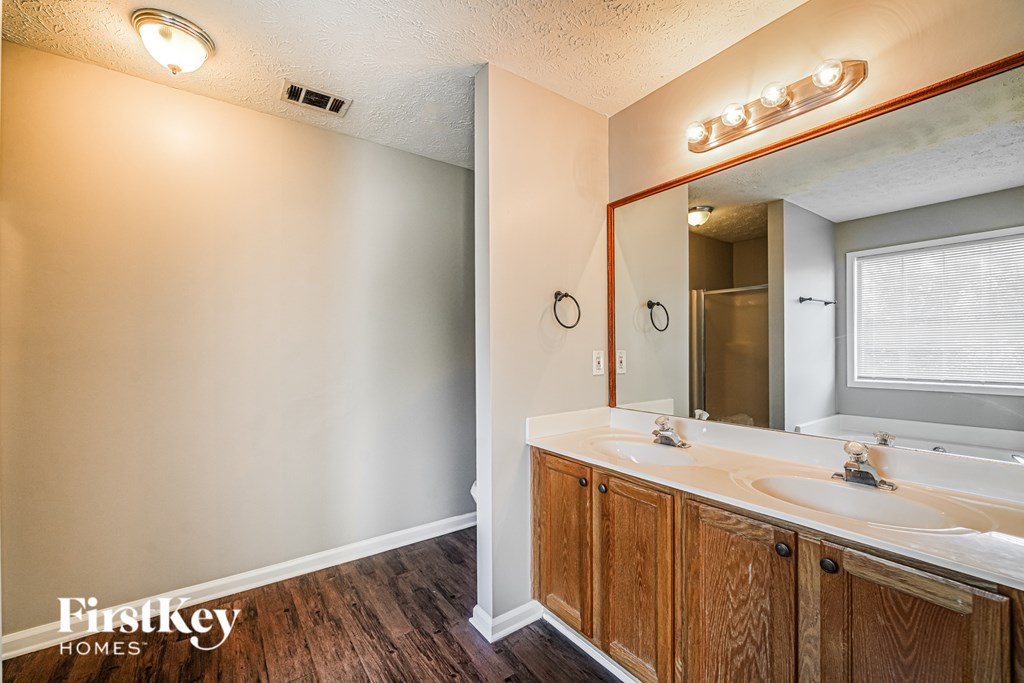 A bathroom with a wooden vanity and a mirror above it.