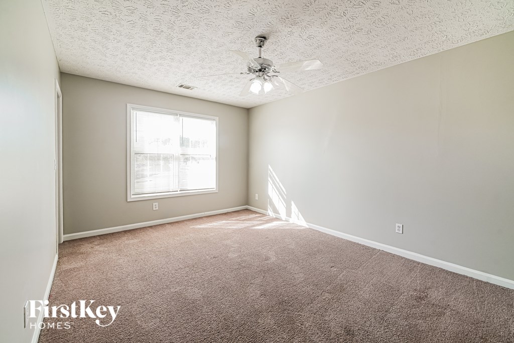 A room with a carpeted floor and a window letting in sunlight.