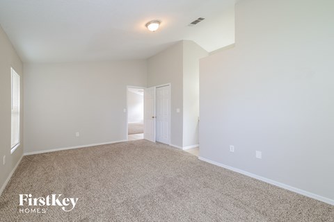 a spacious living room with carpet and a door to a hallway