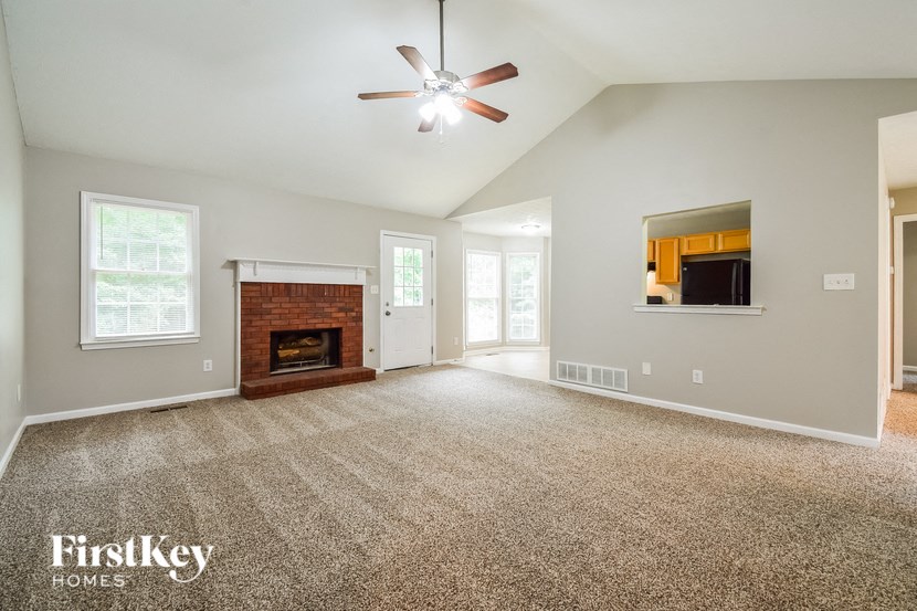 an empty living room with a fireplace and a ceiling fan