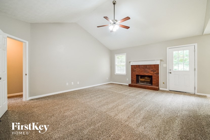 an empty living room with a fireplace and a ceiling fan