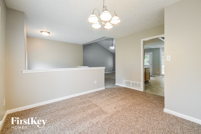an empty living room and dining room with a white wall and carpet
