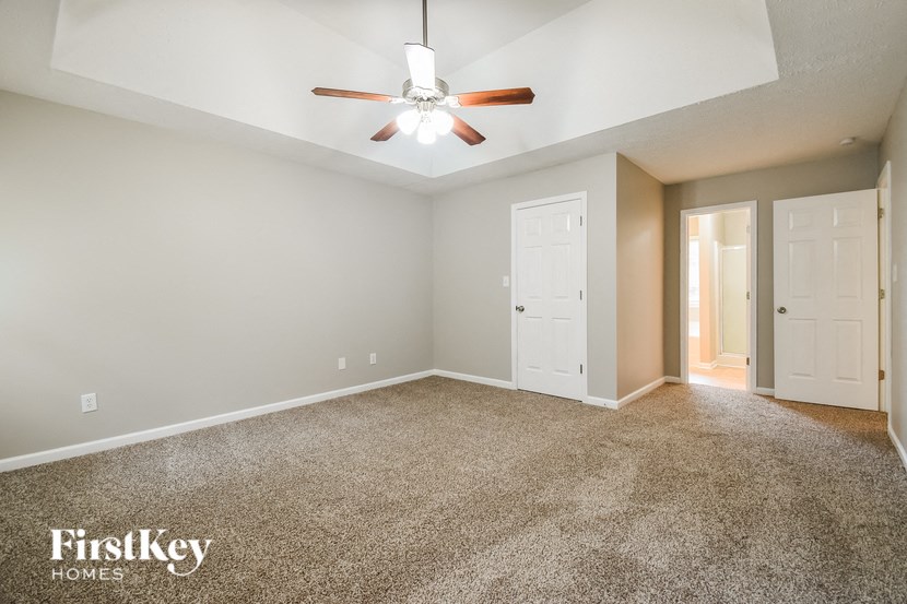 an empty living room with a ceiling fan and a door to a closet