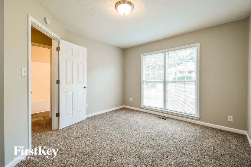 an empty living room with a large window and a white door