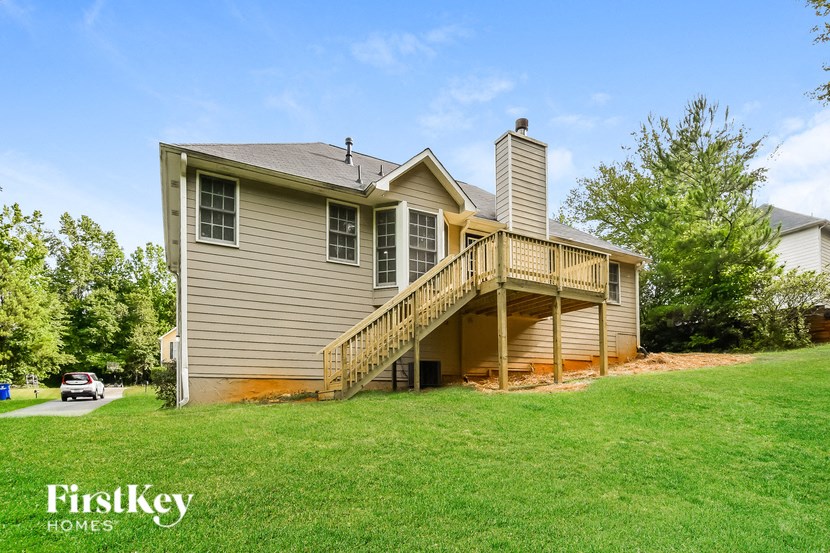 a house with a deck on top of a green lawn