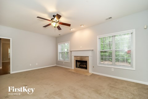 A spacious living room with a fireplace and a ceiling fan.