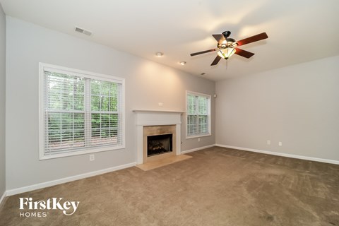 A spacious room with a fireplace and a ceiling fan.