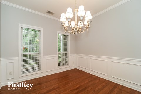 A room with a chandelier and a window with blinds.