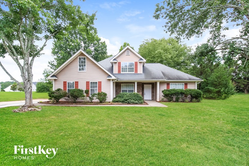 A house with a red and white exterior is surrounded by greenery.