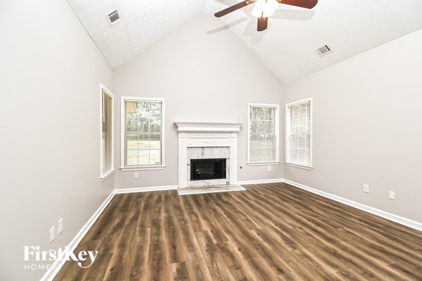 A large empty room with a fireplace and wood flooring.