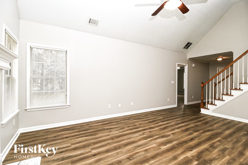A room with wooden floors and a staircase on the right side.