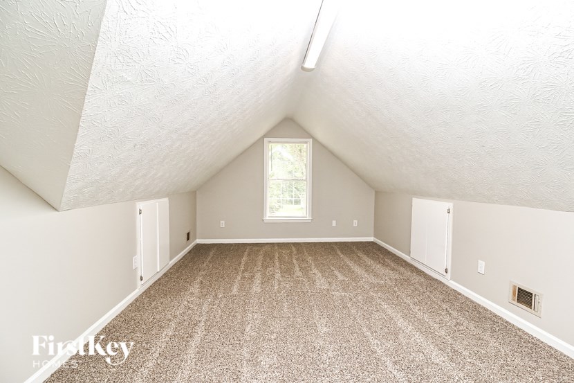 A sparsely furnished room with a window and a skylight.