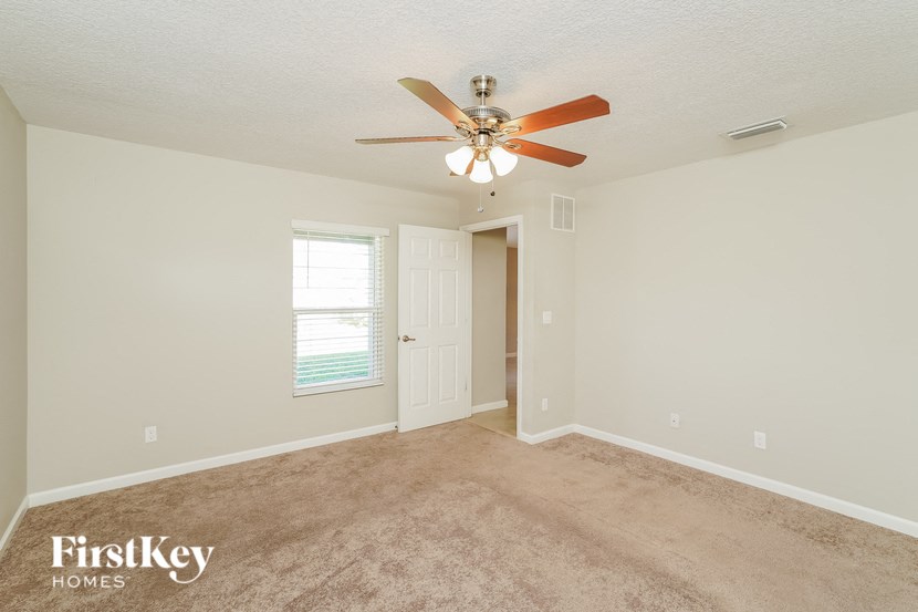 an empty living room with a ceiling fan and a door