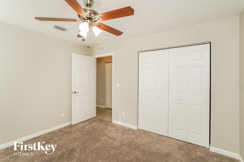 a bedroom with a ceiling fan and a closet