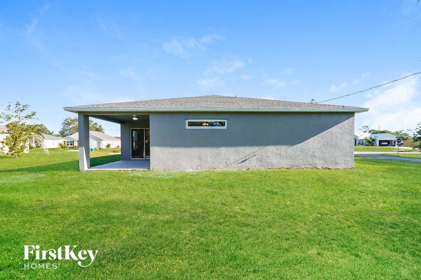 the front of a small gray building with a green lawn