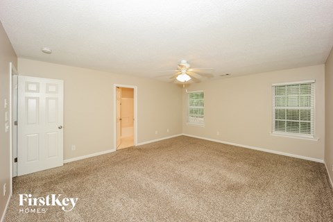 a spacious living room with carpet and a ceiling fan