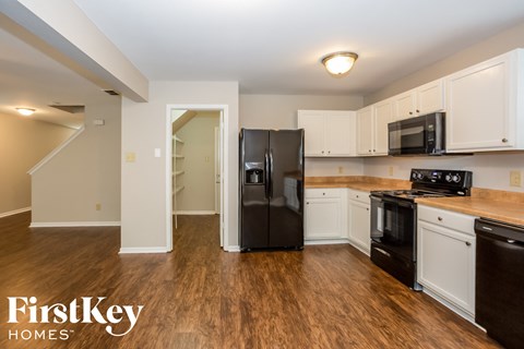 a kitchen with white cabinets and a black refrigerator