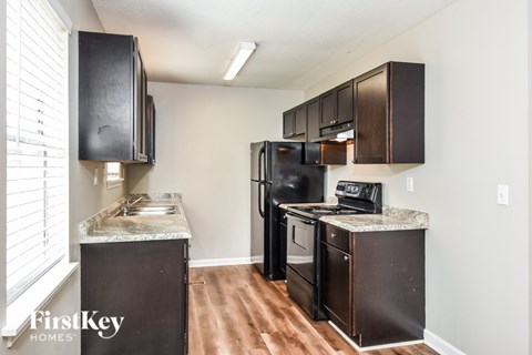 A kitchen with a black fridge and black cabinets.