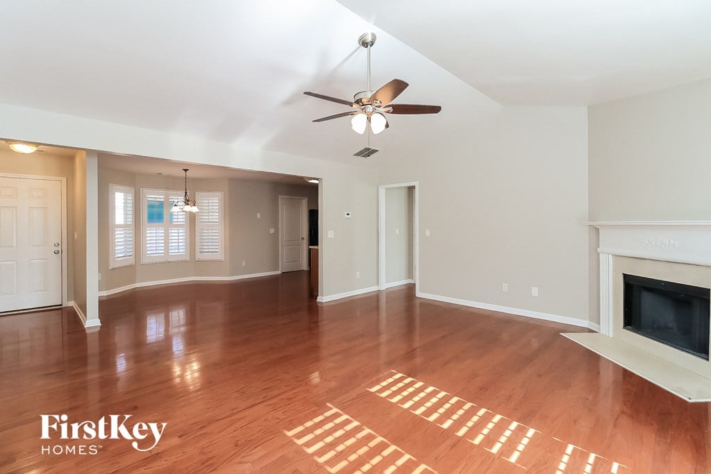 an empty living room with a fireplace and a ceiling fan