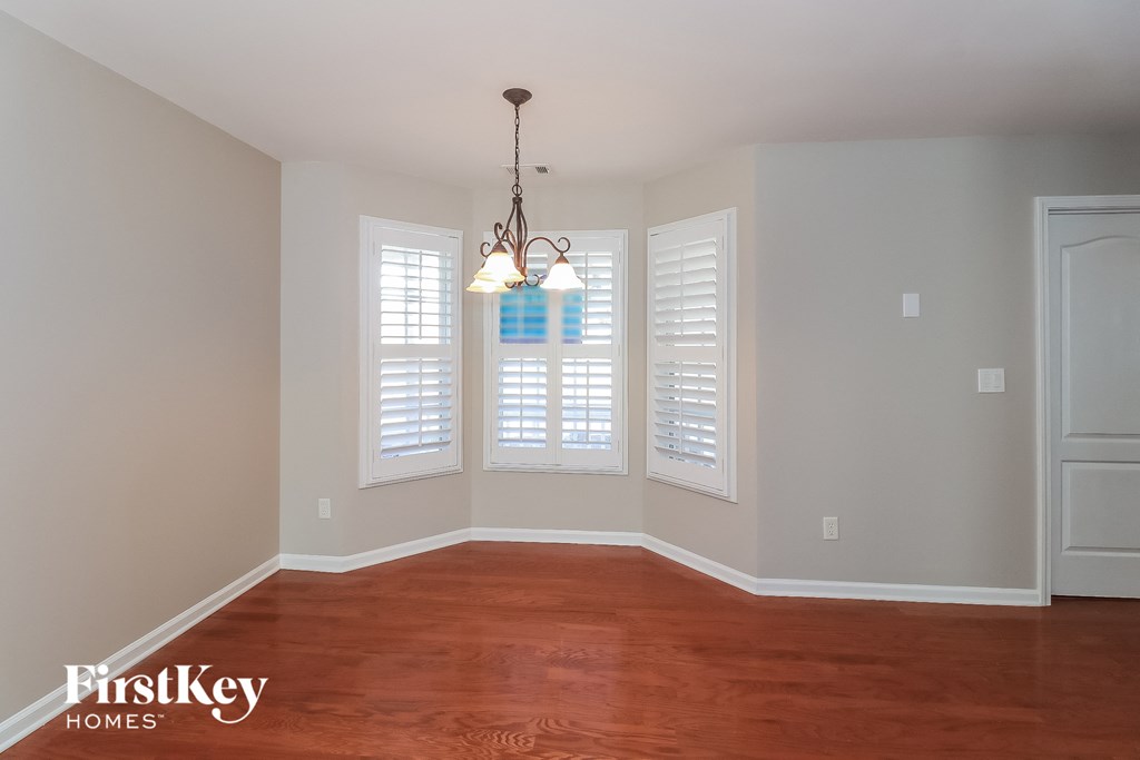 the living room of a home with white shutters and a wood floor