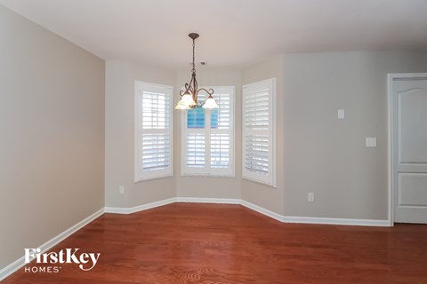 the living room of a home with white shutters and a wood floor
