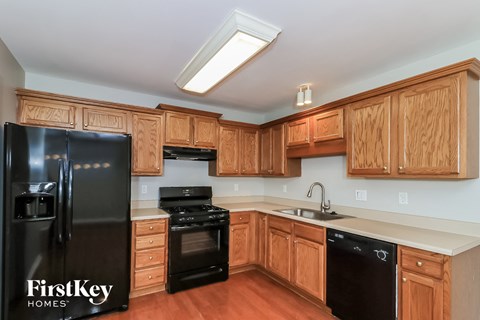 a kitchen with wooden cabinets and black appliances and a black refrigerator