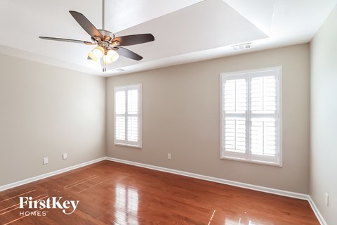 a empty room with a ceiling fan and two windows