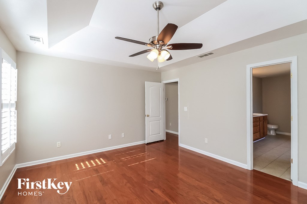 a living room with a ceiling fan and a door to a bathroom