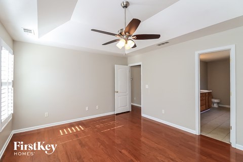 a living room with a ceiling fan and a door to a bathroom