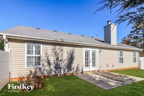 the backyard of a small house with a yard and a driveway