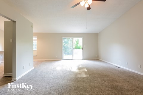 A spacious room with a carpeted floor and a ceiling fan.