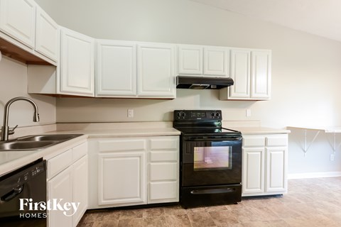 A kitchen with white cabinets and a black stove top oven.