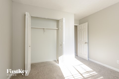A white bedroom with a large open closet door.