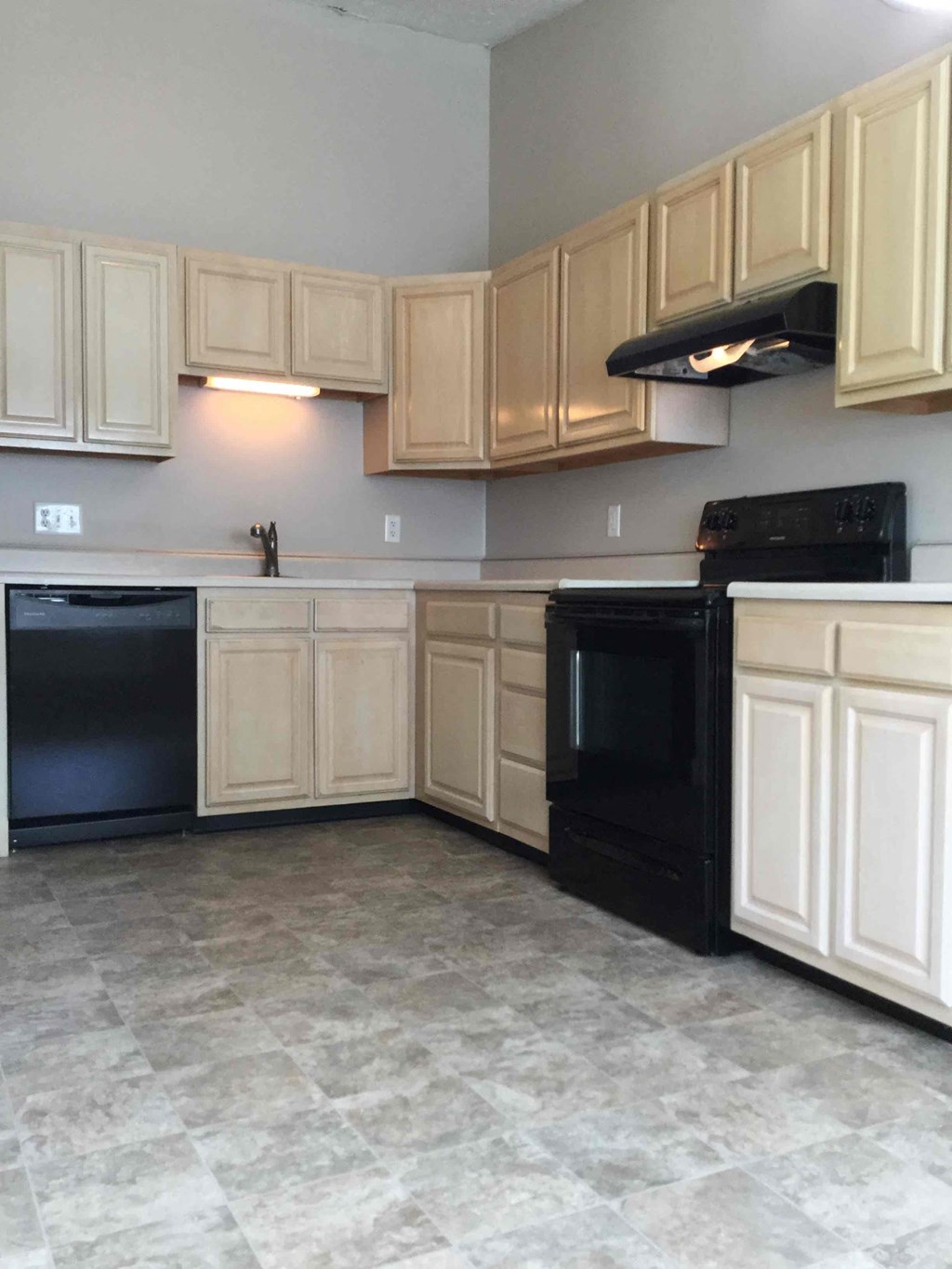 A kitchen with black appliances and wooden cabinets.