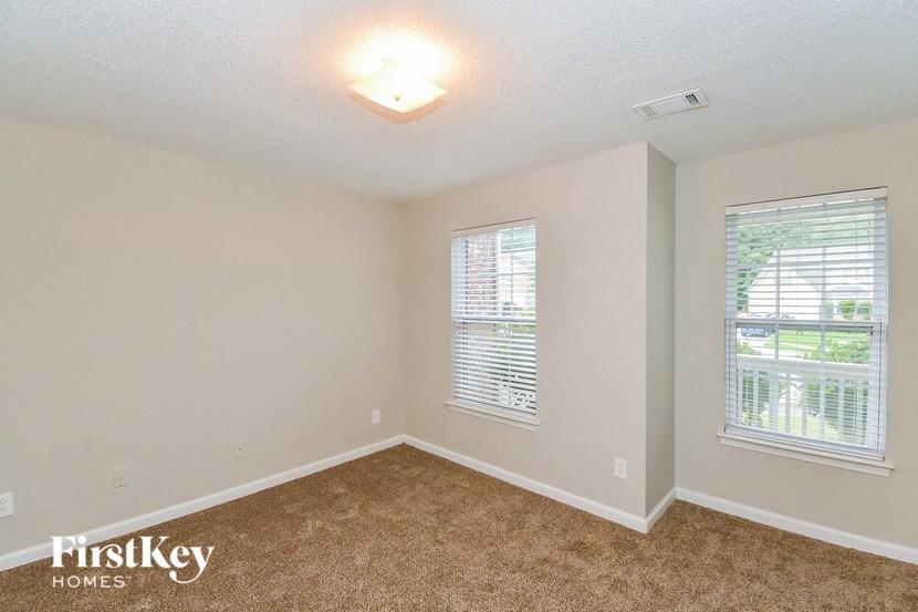 a bedroom with a carpeted floor and two windows