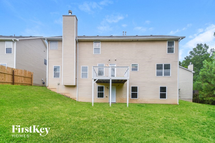 a white house with a balcony on a green lawn