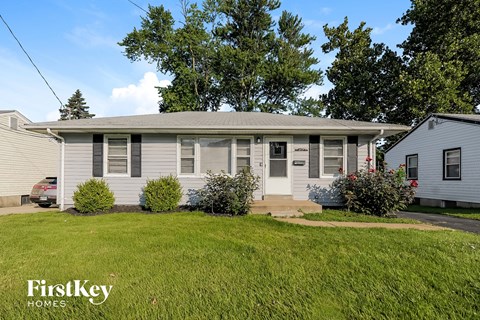 A house with a grey roof and a white door is surrounded by green grass.