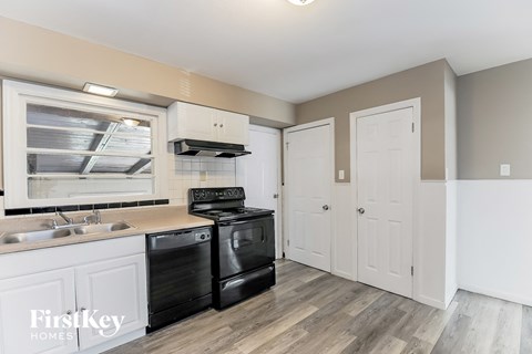 A kitchen with a black stove top oven and white cabinets.
