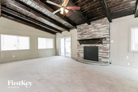 A spacious room with a fireplace and a ceiling fan.