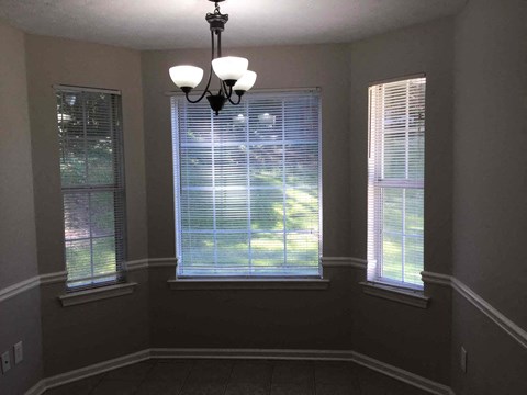 a dining room with three windows and a chandelier
