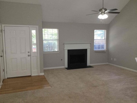 an empty living room with a fireplace and a ceiling fan