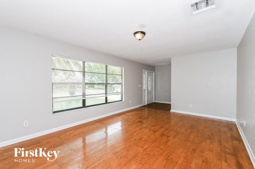 an empty living room with wood floors and a large window
