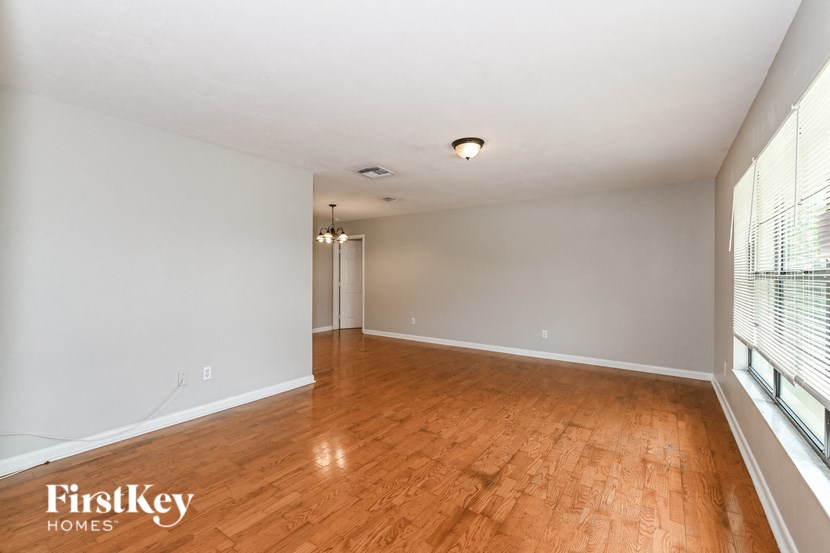 an empty living room with wood flooring and a large window