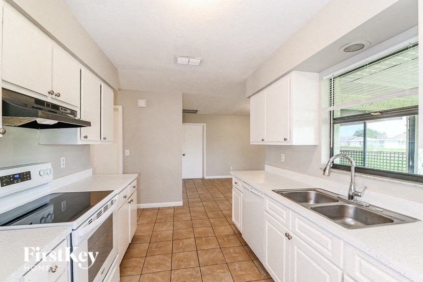 a kitchen with white cabinets and a sink and a window